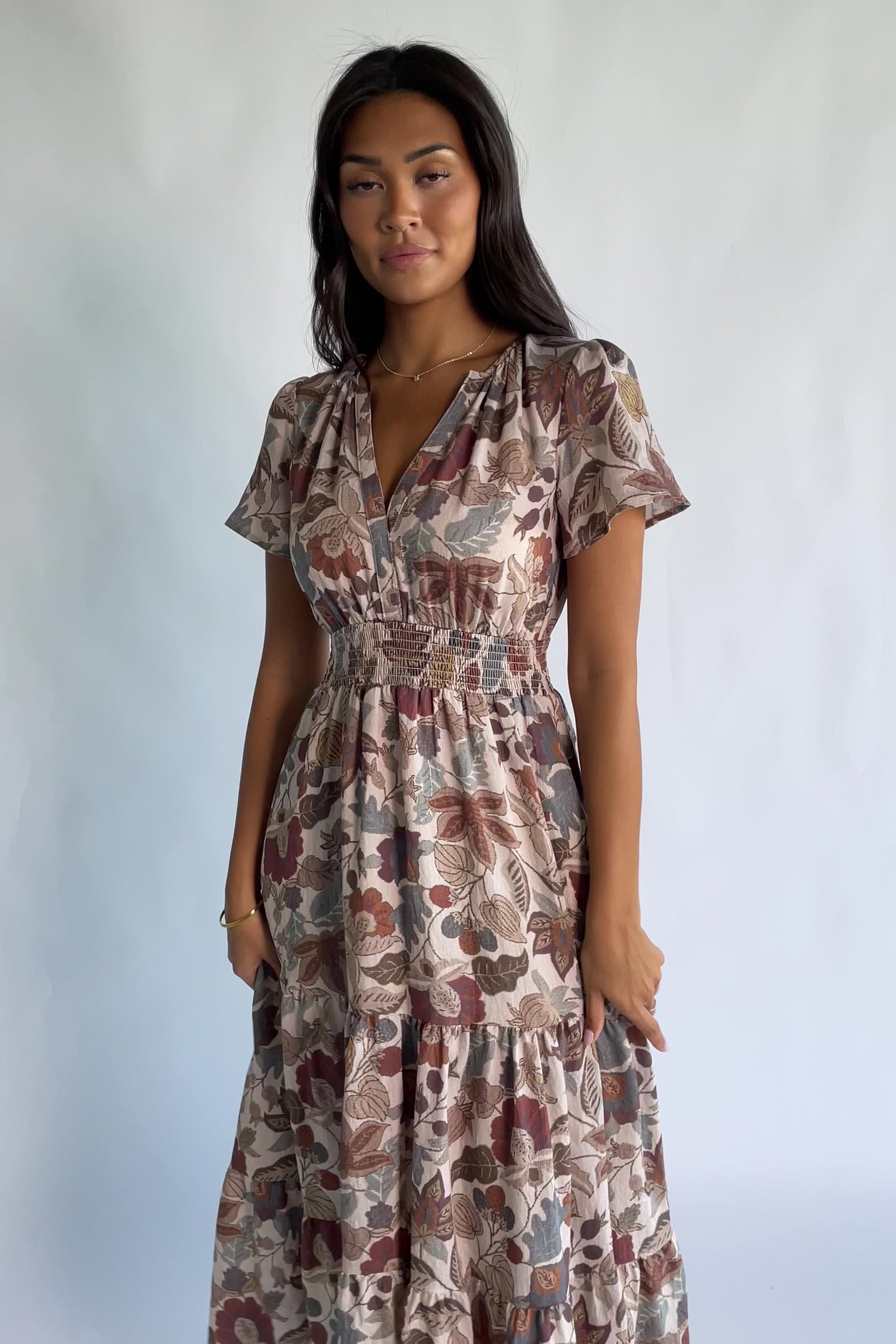 Holland Dress in Taupe Multi with a smocked waist, V-neckline, flutter sleeves, and a floral print.