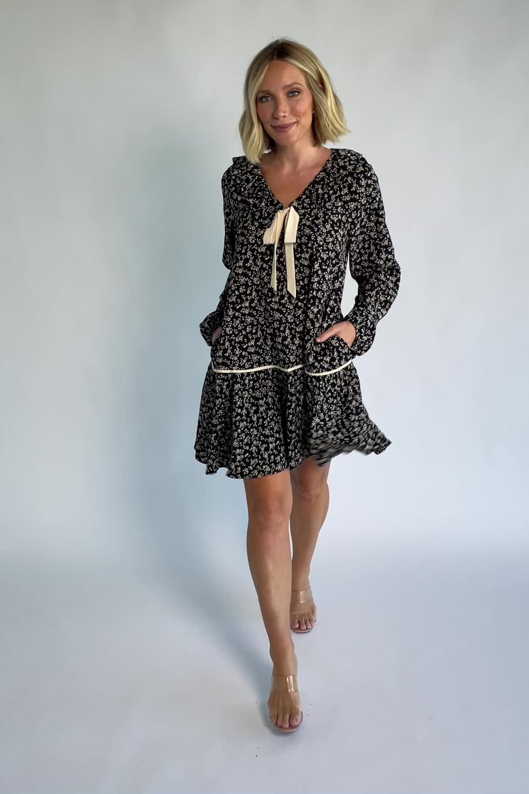 Shantel Bow Front Short Dress in Black Floral with ruffled neckline, faux bow front, long sleeves, and short skirt.