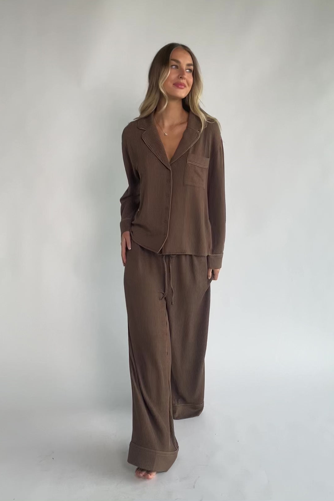 Brown ribbed pajama set with a button-front V-neck top, long sleeves, chest pocket, and wide-leg pants with an elastic drawstring waist.