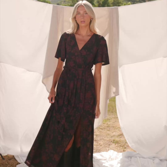 Reverie Maxi Dress in Black + Burgundy with floral print, surplice V-neck, sash waist, long sleeves, and side leg slit.