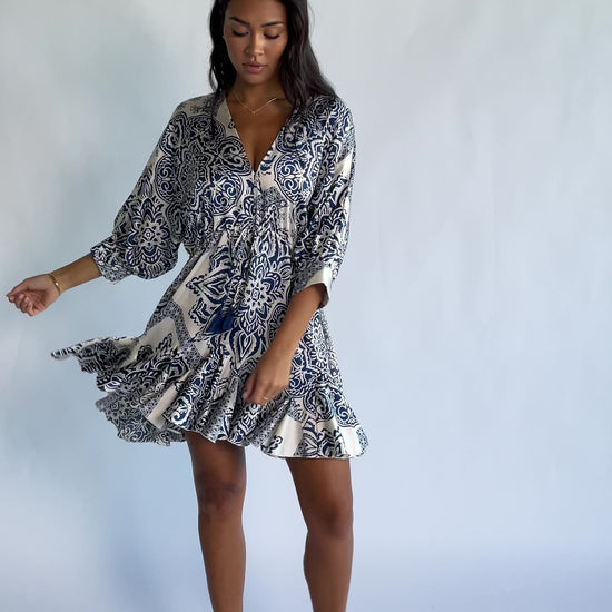 Morwen Short Dress in Navy Print with a V-neckline front and back, batwing sleeves, and a ruffled paneled skirt.
