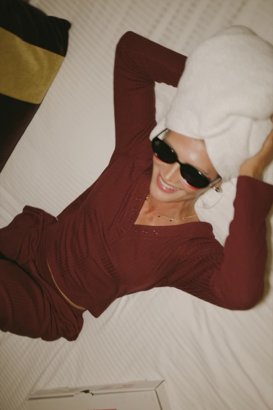 Model wearing the Rubi Soft Ribbed Pajama Set in Burgundy featuring a soft ribbed knit, long-sleeve V-neck top with a snap-button placket, and matching straight-leg pants with an elastic waistband and side pockets.