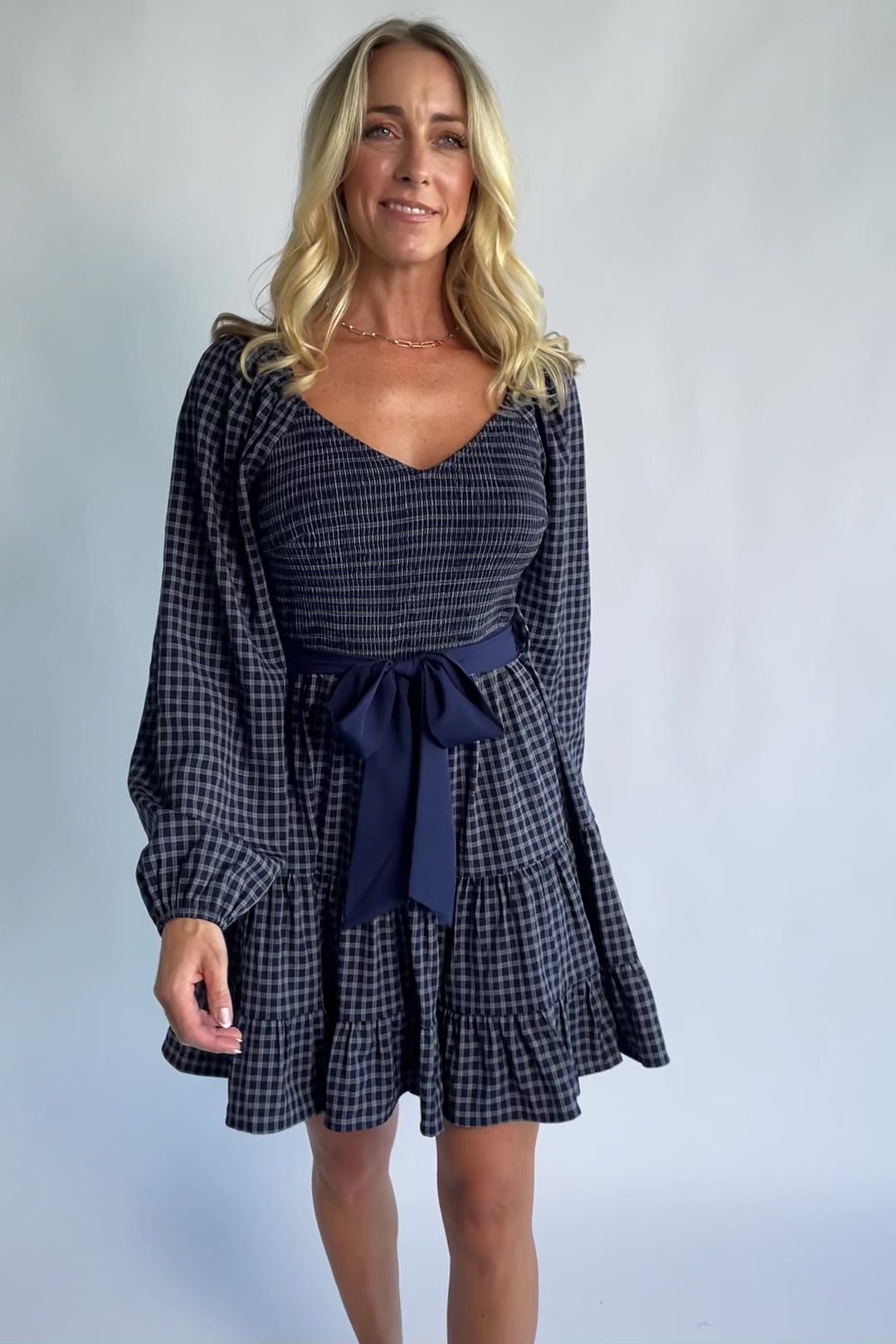 Stina Short Dress in Navy Plaid with smocked V-neck bodice, long sleeves, and tiered skirt.
