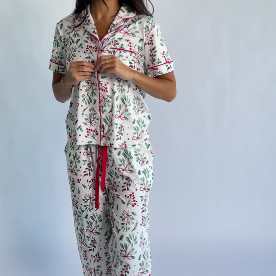 Mistletoe Cozy Pajama Set in Ivory Multi with a festive mistletoe and holly print, button-front top, and contrast piping.