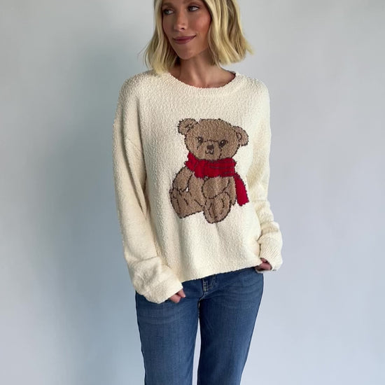 Junie Cozy Bear Sweater in Ivory with teddy bear graphic, red scarf, crew neckline, and ribbed trim.