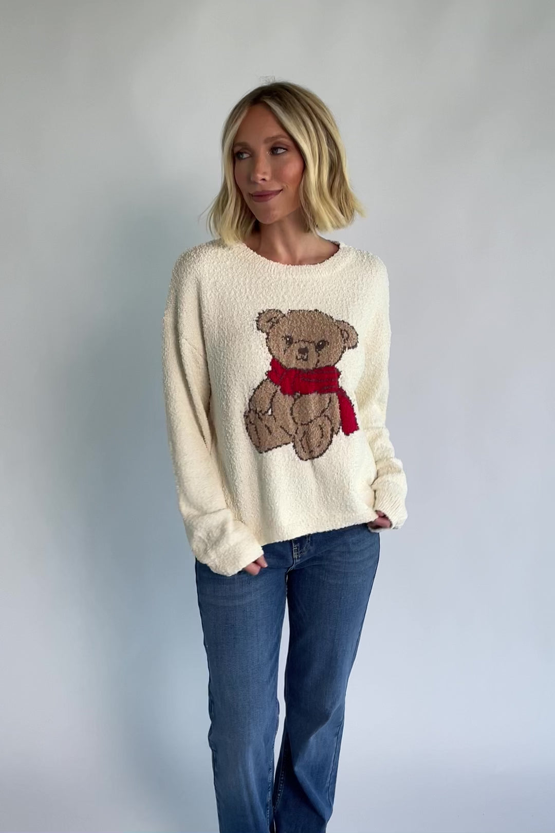 Junie Cozy Bear Sweater in Ivory with teddy bear graphic, red scarf, crew neckline, and ribbed trim.