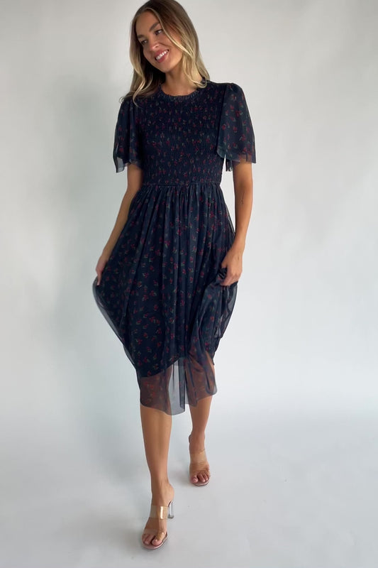 Navy floral mesh midi dress with a high ruffle neckline, flutter sleeves, full smocked bodice, and flowing midi skirt.