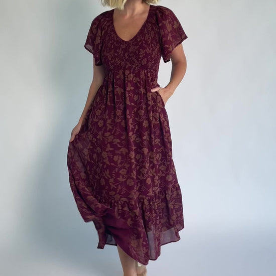 Monica Smocked Dress in Wine + Gold with V-neckline, smocked bodice, flutter sleeves, high waist, and tiered skirt.