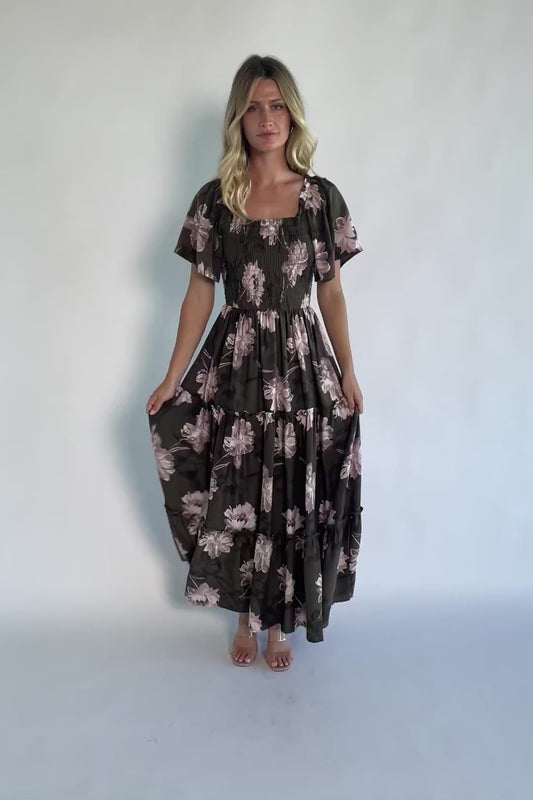 Dark olive floral maxi dress with a smocked bodice, square neckline, flutter sleeves, and a tiered ruffle skirt.