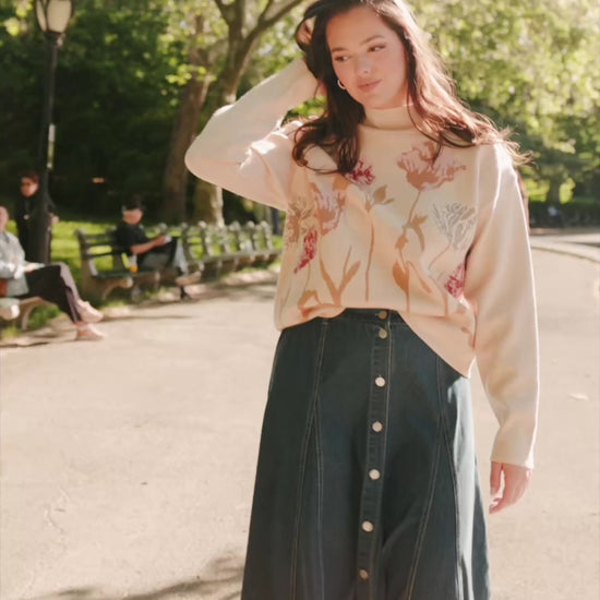 Natural knit sweater with a mock neckline, long sleeves, relaxed fit, and an embroidered floral motif at the neckline.