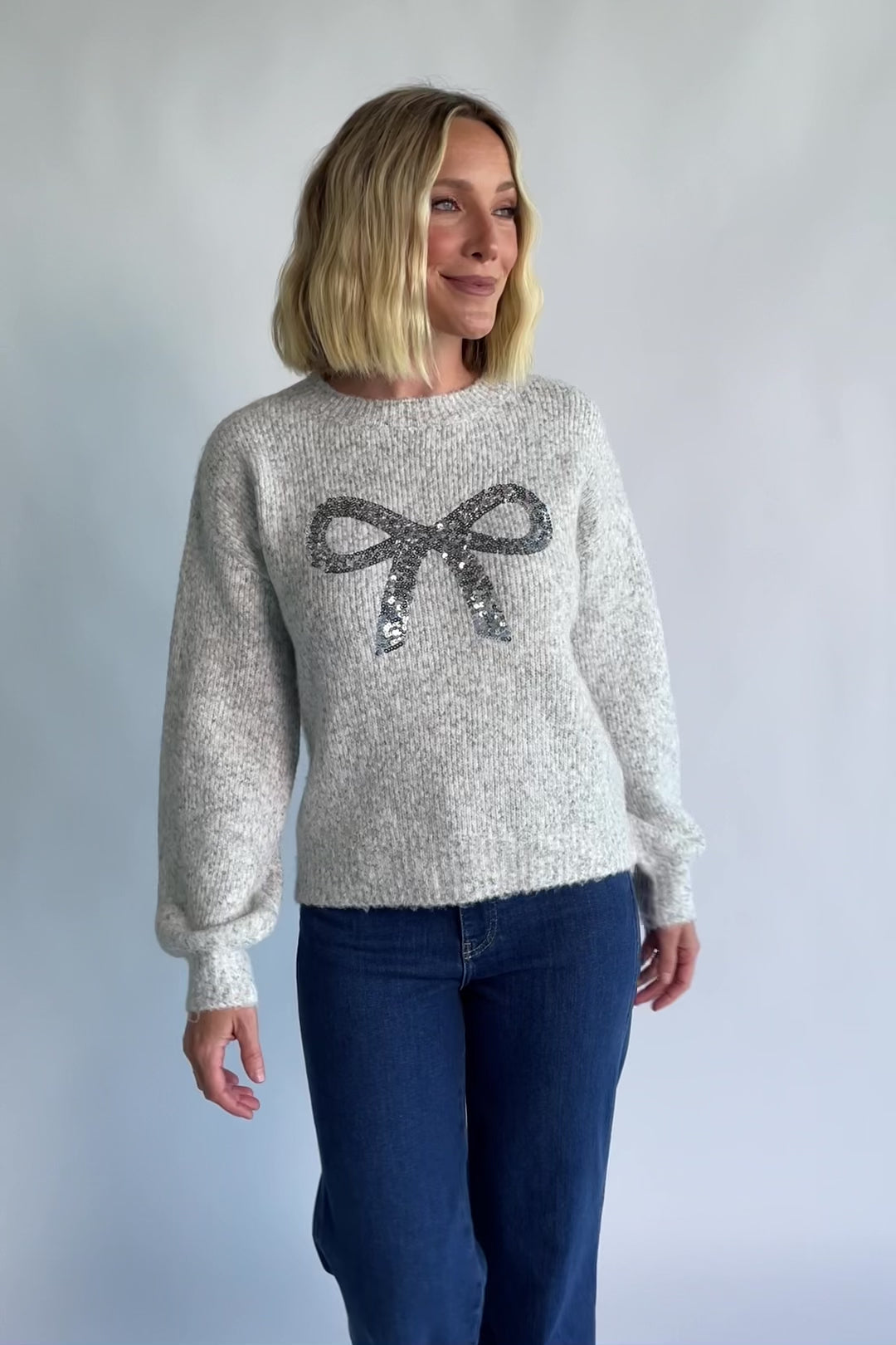 Bow Sweater in Gray with a sparkling sequin bow at the front, a crew neckline, and a heathered knit finish.