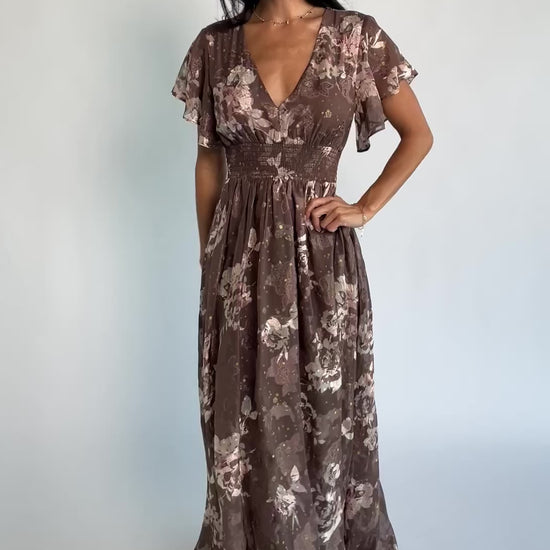 Mocha metallic floral chiffon maxi dress with a V-neckline, flutter sleeves, smocked waist, and flowing full-length skirt.