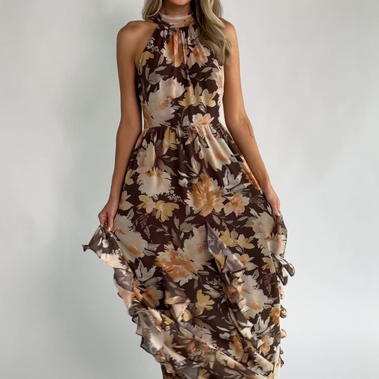 Brown and golden floral chiffon maxi dress with a high halter neckline, cascading ruffle details, smocked back waistband, and a flowing silhouette.