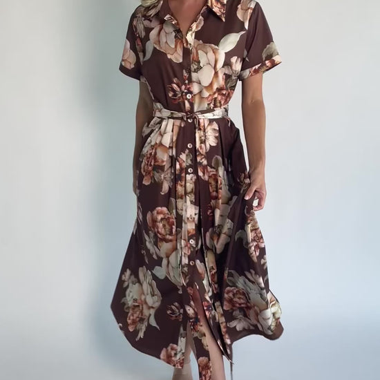 Model wearing the Blythe Midi Dress in Brown Floral featuring a collared neckline, functional button-front bodice, short rolled sleeves, and a removable waist tie.