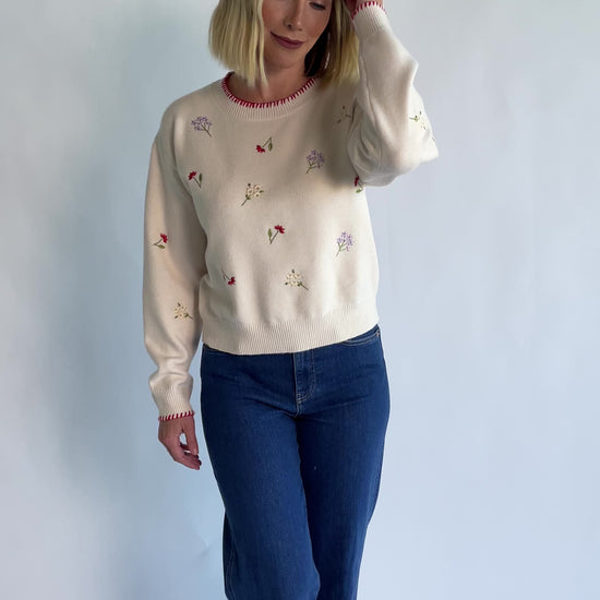 Ottilie Sweater in Cream with embroidered floral details, round neckline, red knit piping, and long sleeves.