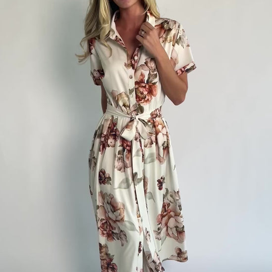 Model wearing the Blythe Midi Dress in Ivory Floral featuring a collared neckline, functional button-front bodice, short rolled sleeves, and a removable waist tie.