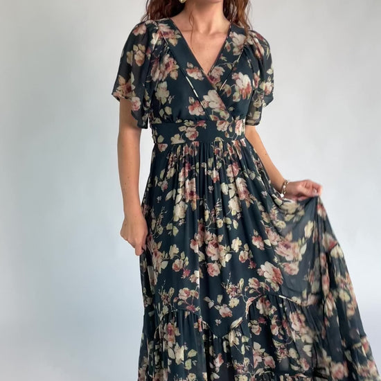 Katherine Maxi Dress in Deep Blue Floral with surplice V-neck, flutter sleeves, adjustable waist ties, and tiered skirt.