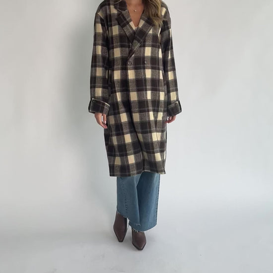 Brown plaid double-breasted longline coat with a collared lapel neckline, side pockets, back slit, and relaxed tailored fit.