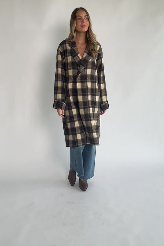 Brown plaid double-breasted longline coat with a collared lapel neckline, side pockets, back slit, and relaxed tailored fit.
