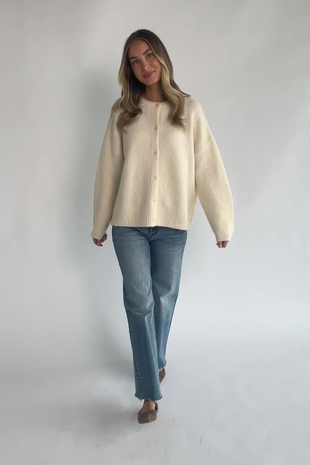 Cream fuzzy knit cardigan with a round neckline, button-front closure, long sleeves, dropped shoulders, and a relaxed fit.