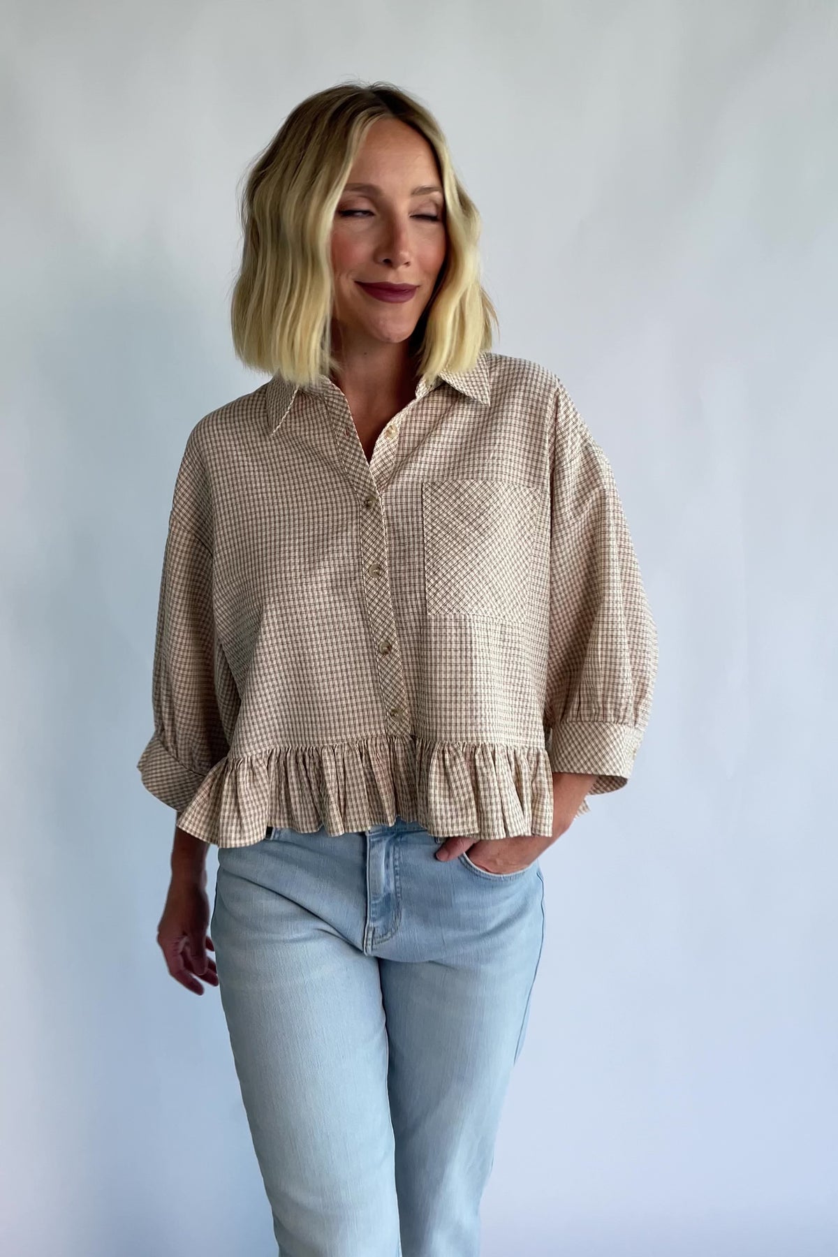 Murphy Relaxed Peplum Top in Beige with a collared neckline, button-front closure, chest pocket, and peplum hem.