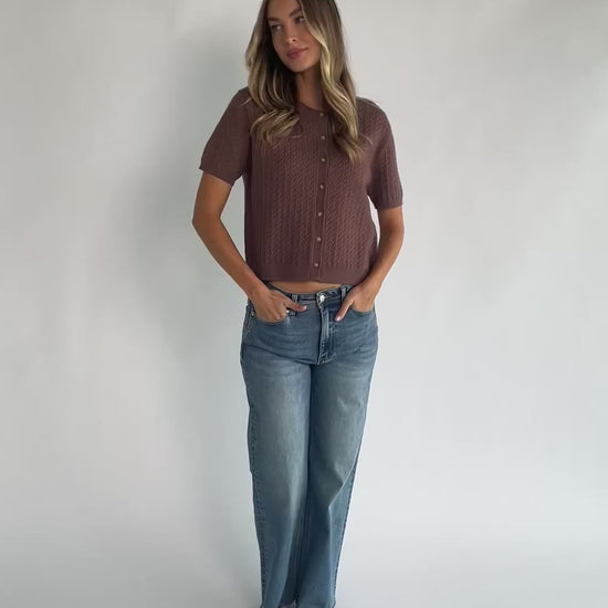 Brown cable knit cardigan with a round neckline, short sleeves, button-front closure, ribbed trim, and a relaxed fit.