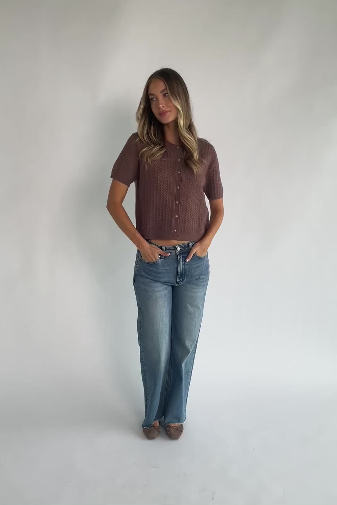 Brown cable knit cardigan with a round neckline, short sleeves, button-front closure, ribbed trim, and a relaxed fit.