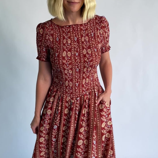 Rhonda Smocked Midi Dress in Rust Print with a round neckline, smocked bodice, and ruffled sleeve edges.