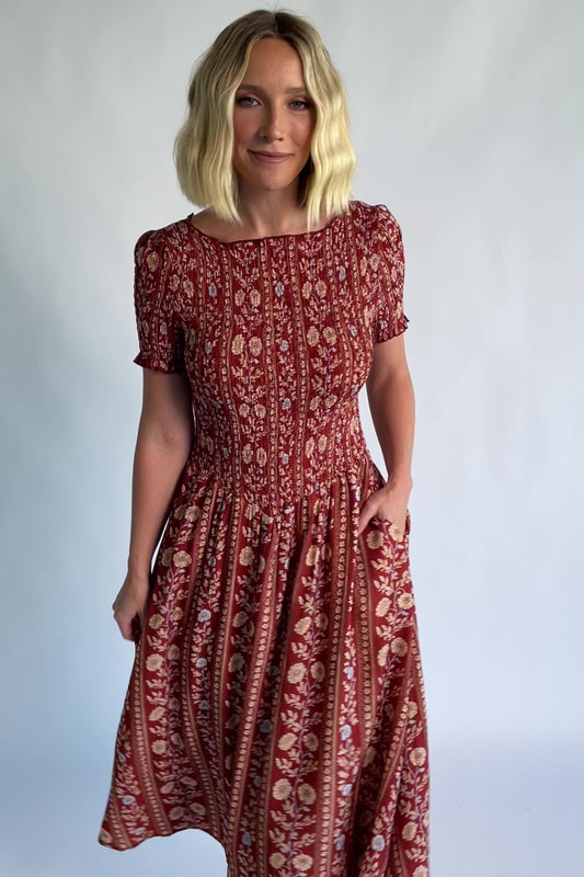 Rhonda Smocked Midi Dress in Rust Print with a round neckline, smocked bodice, and ruffled sleeve edges.