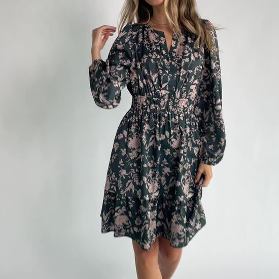 Green floral long sleeve mini dress with a notched V-neckline, elastic waist, tiered skirt, side pockets, and a lined skirt.