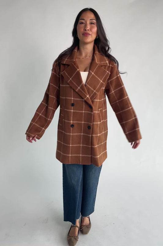 Cognac plaid mid-length coat with a cream windowpane pattern, tailored collar, button-front closure, long sleeves, front pockets, and a fully lined interior.