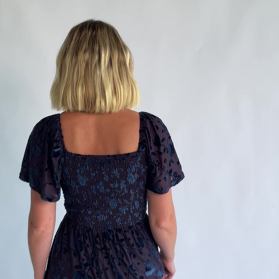 Amoret Midi Dress in Midnight Navy Floral with raised velvet florals, a sweetheart neckline, and flutter sleeves.