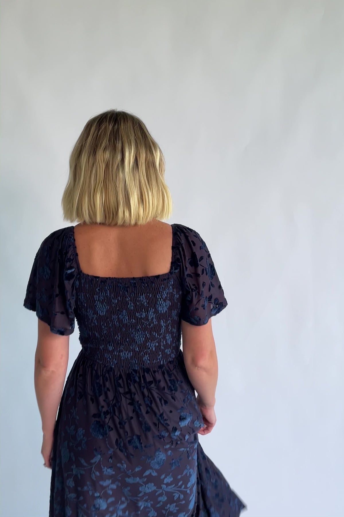 Amoret Midi Dress in Midnight Navy Floral with raised velvet florals, a sweetheart neckline, and flutter sleeves.