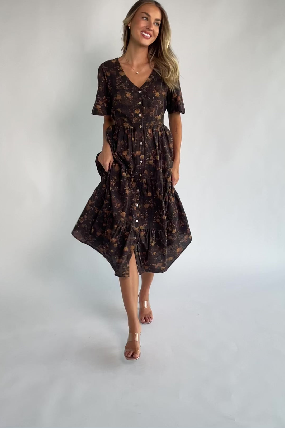 Clove floral midi dress with a V-neckline, functional button-front closure, puff sleeves, elastic back waist, side pockets, and a tiered skirt.