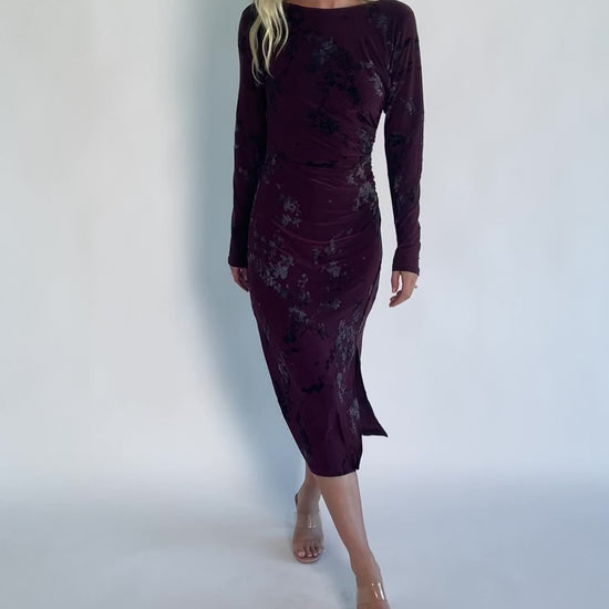 Model wearing a dark plum velvet floral midi dress with a boat neckline, long sleeves, and a fitted silhouette.
