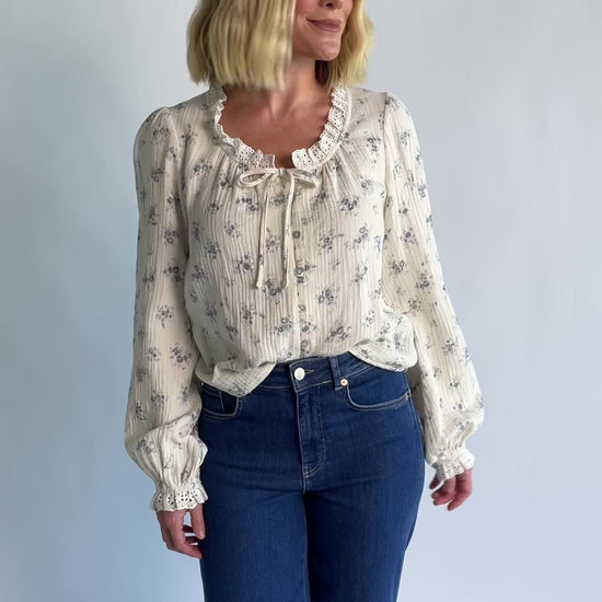 Stephanie Button Front Blouse in Ivory + Blue Floral with a lace-trimmed tie neckline and a button-front design.