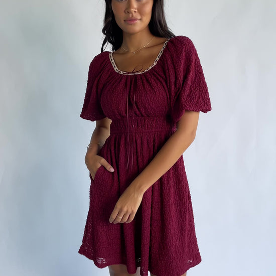 Gwyneth Short Dress in Burgundy with textured floral lace, scoop neckline, cream lace piping, and elastic sleeve cuffs.