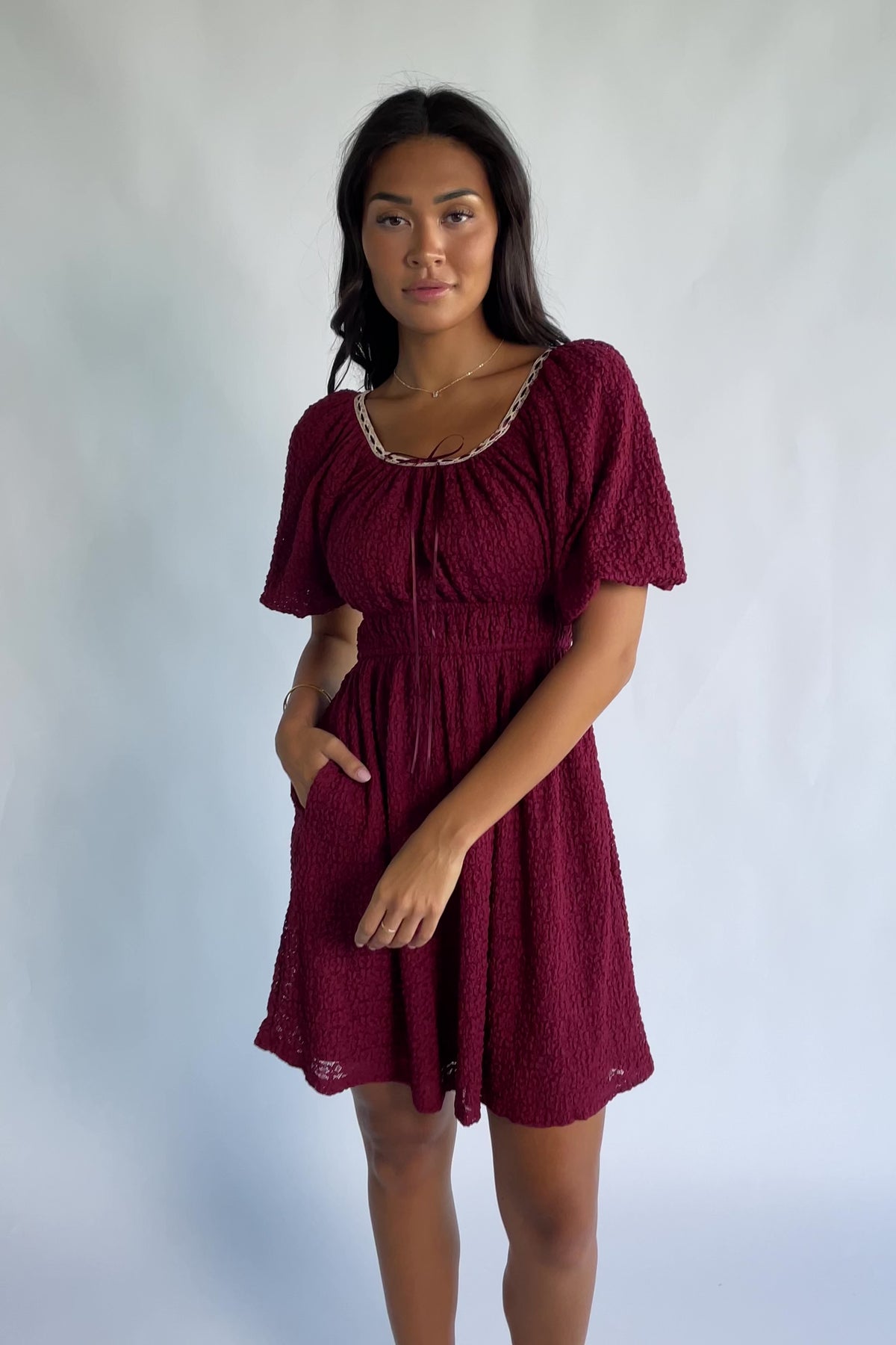 Gwyneth Short Dress in Burgundy with textured floral lace, scoop neckline, cream lace piping, and elastic sleeve cuffs.