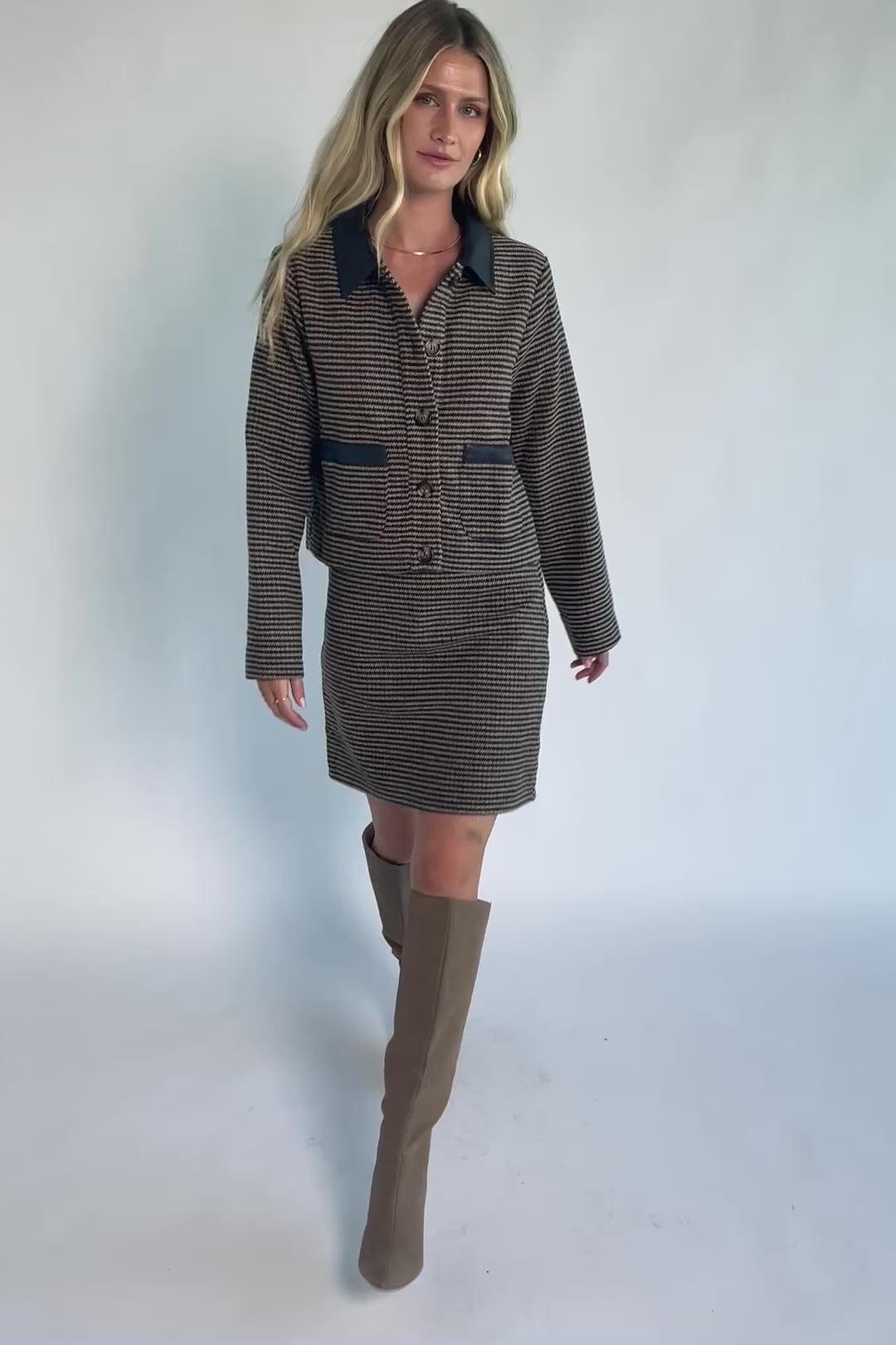Model wearing the Gracey Set in Navy + Tan featuring a navy and tan striped tweed jacket with a collared neckline, faux leather trim, button-front closure, and matching mini skirt for a polished, coordinated look.