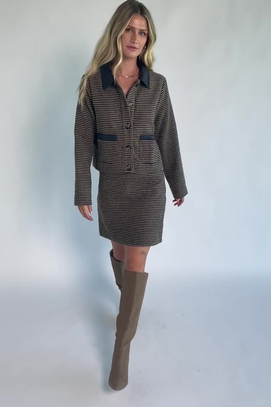 Model wearing the Gracey Set in Navy + Tan featuring a navy and tan striped tweed jacket with a collared neckline, faux leather trim, button-front closure, and matching mini skirt for a polished, coordinated look.