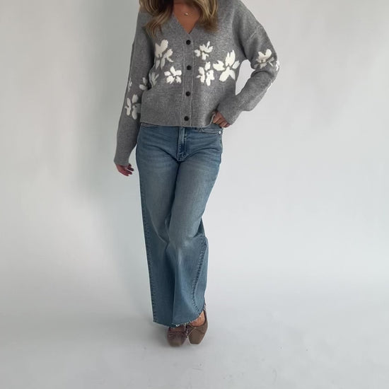 Gray floral knit cardigan with a V-neckline, button-front closure, long sleeves, ribbed trim, and a relaxed silhouette.