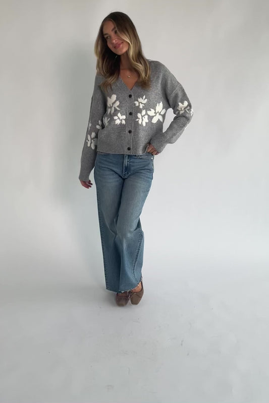 Gray floral knit cardigan with a V-neckline, button-front closure, long sleeves, ribbed trim, and a relaxed silhouette.
