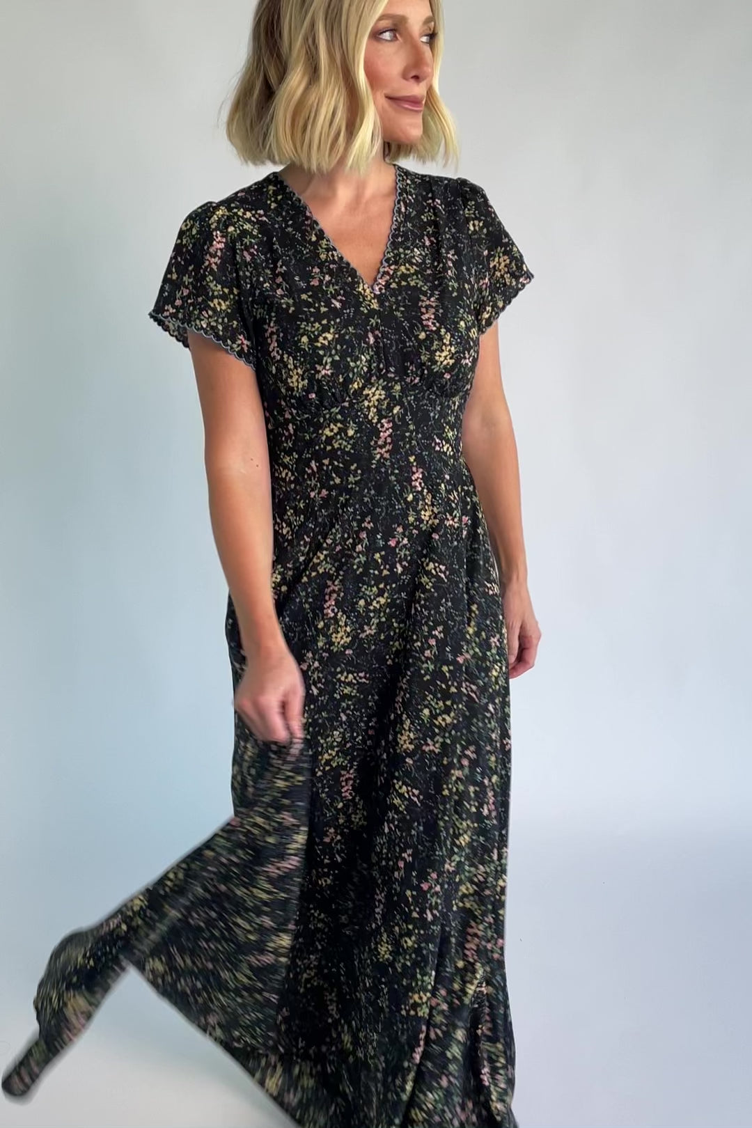 Jada Maxi Dress in Black Floral with V-neckline, blue scalloped trim, flutter sleeves, empire waist, and tie waist.