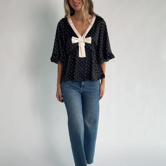 Carrie Bow Front Top in Black + Ivory Dot with contrast collar, bow detail, V-neck, ruffle sleeves, and peplum hem.