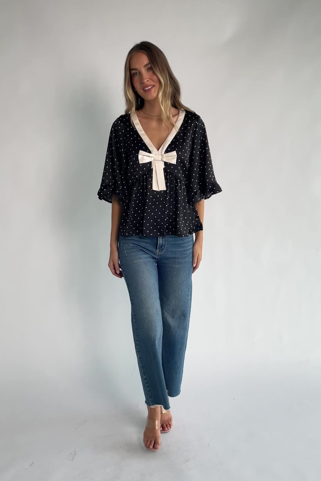 Carrie Bow Front Top in Black + Ivory Dot with contrast collar, bow detail, V-neck, ruffle sleeves, and peplum hem.