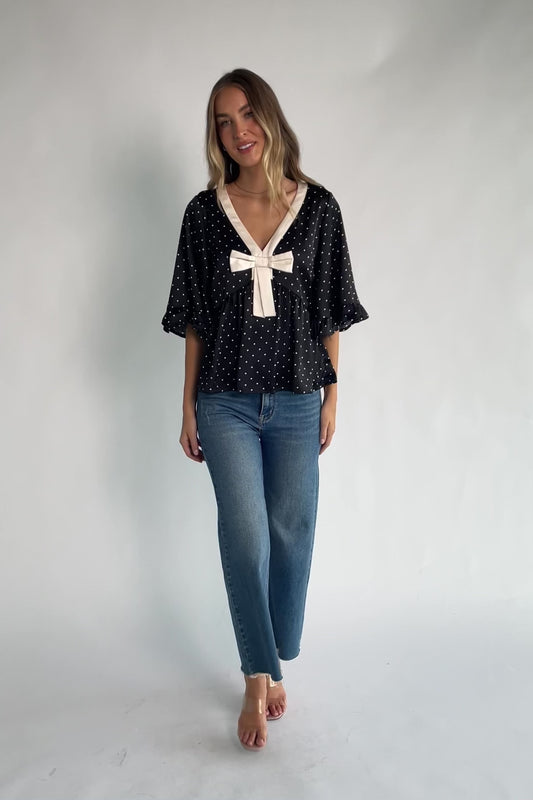Carrie Bow Front Top in Black + Ivory Dot with contrast collar, bow detail, V-neck, ruffle sleeves, and peplum hem.