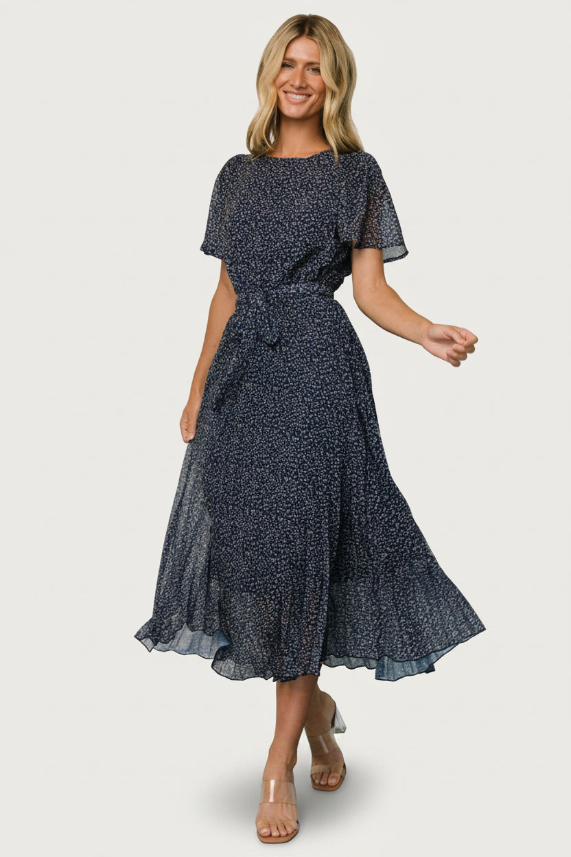 Styled view of Prim Pleated Midi Dress in navy leaf print on model, showing midi length, pleated movement, and modest silhouette.