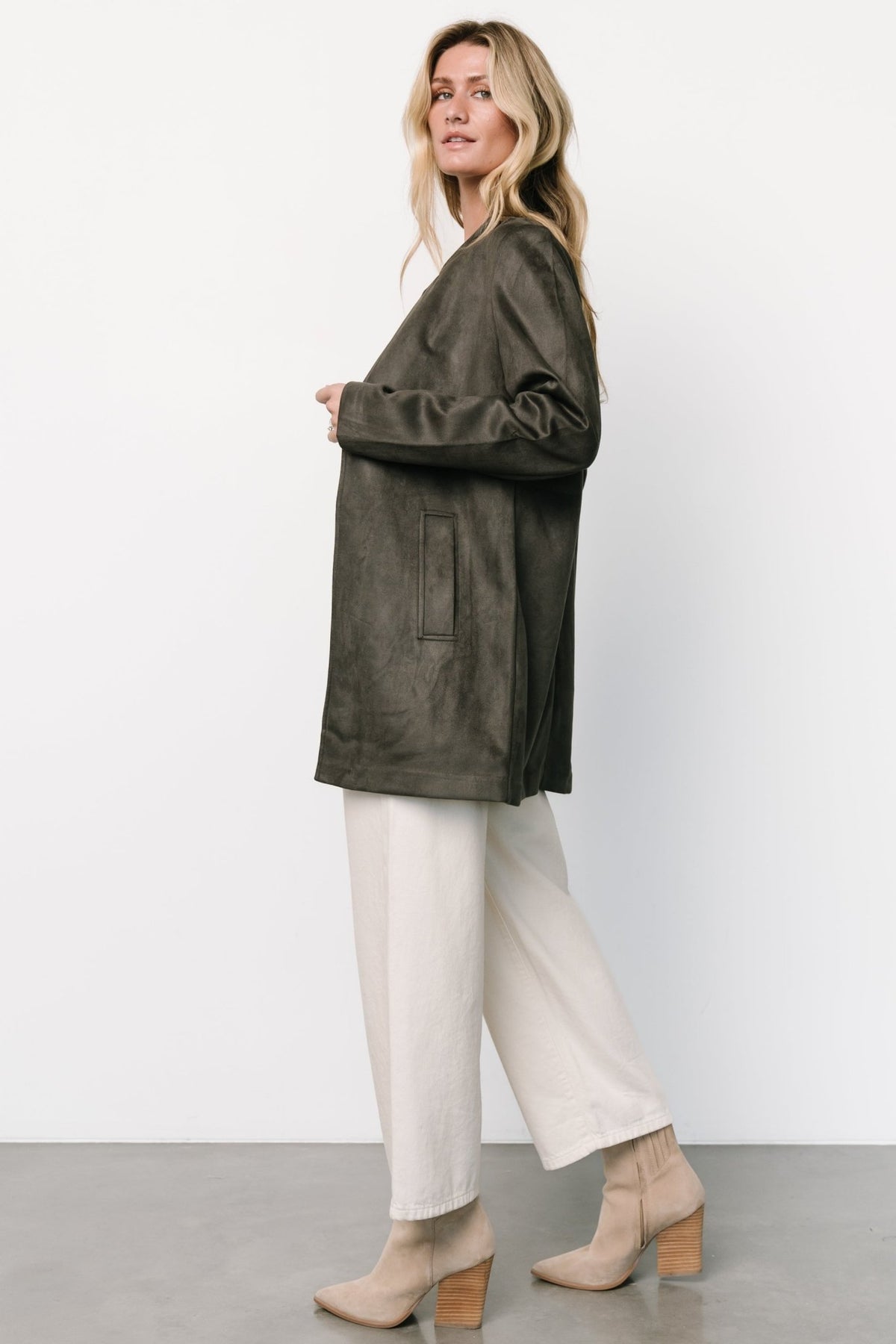 Detail of hook-and-eye closures and deep V front, highlighting clean lines and discreet fastenings on the jacket.