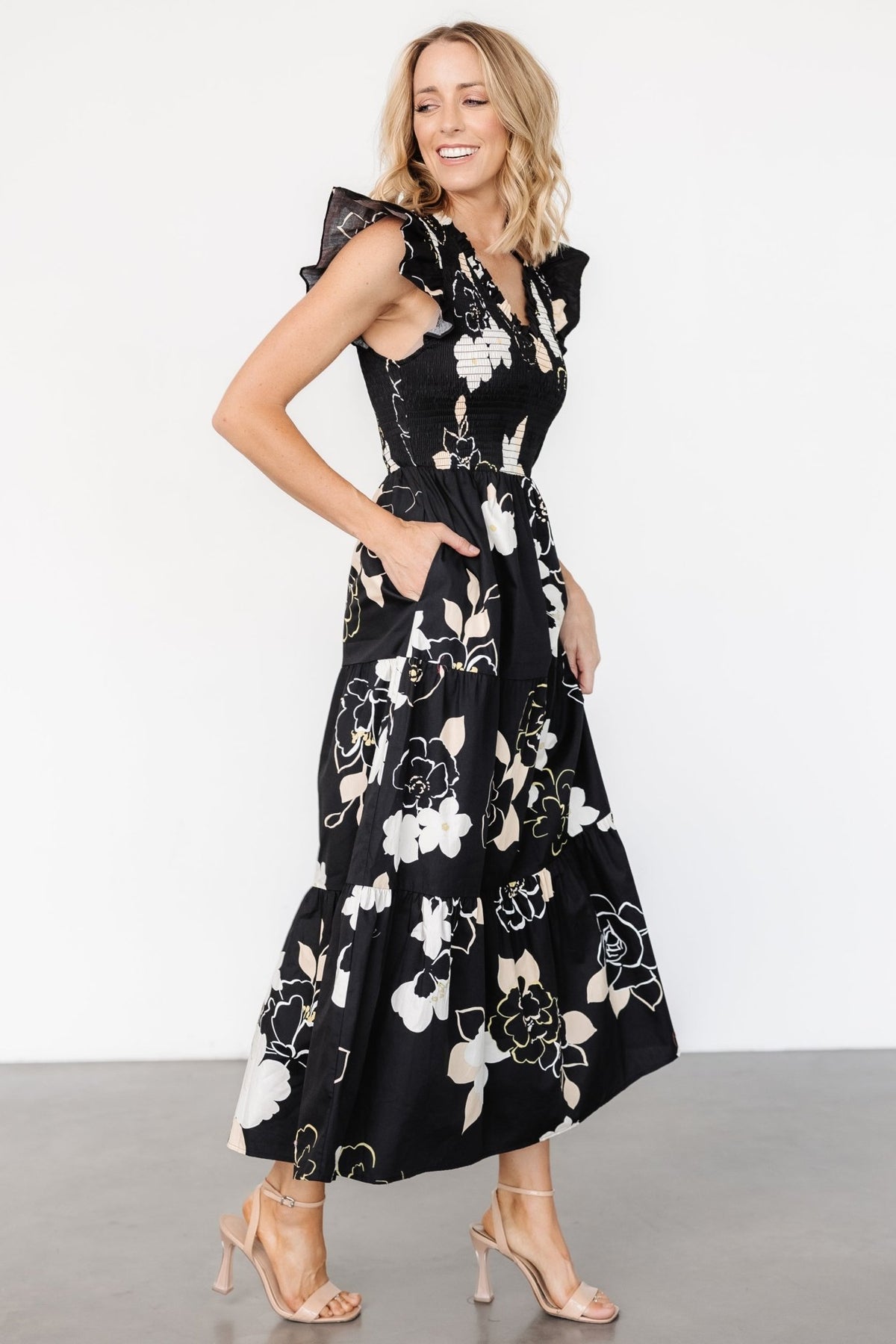 Close-up of smocked bodice and ruffled V-neck of the Ranchero maxi dress in black floral print to show texture and stretch.