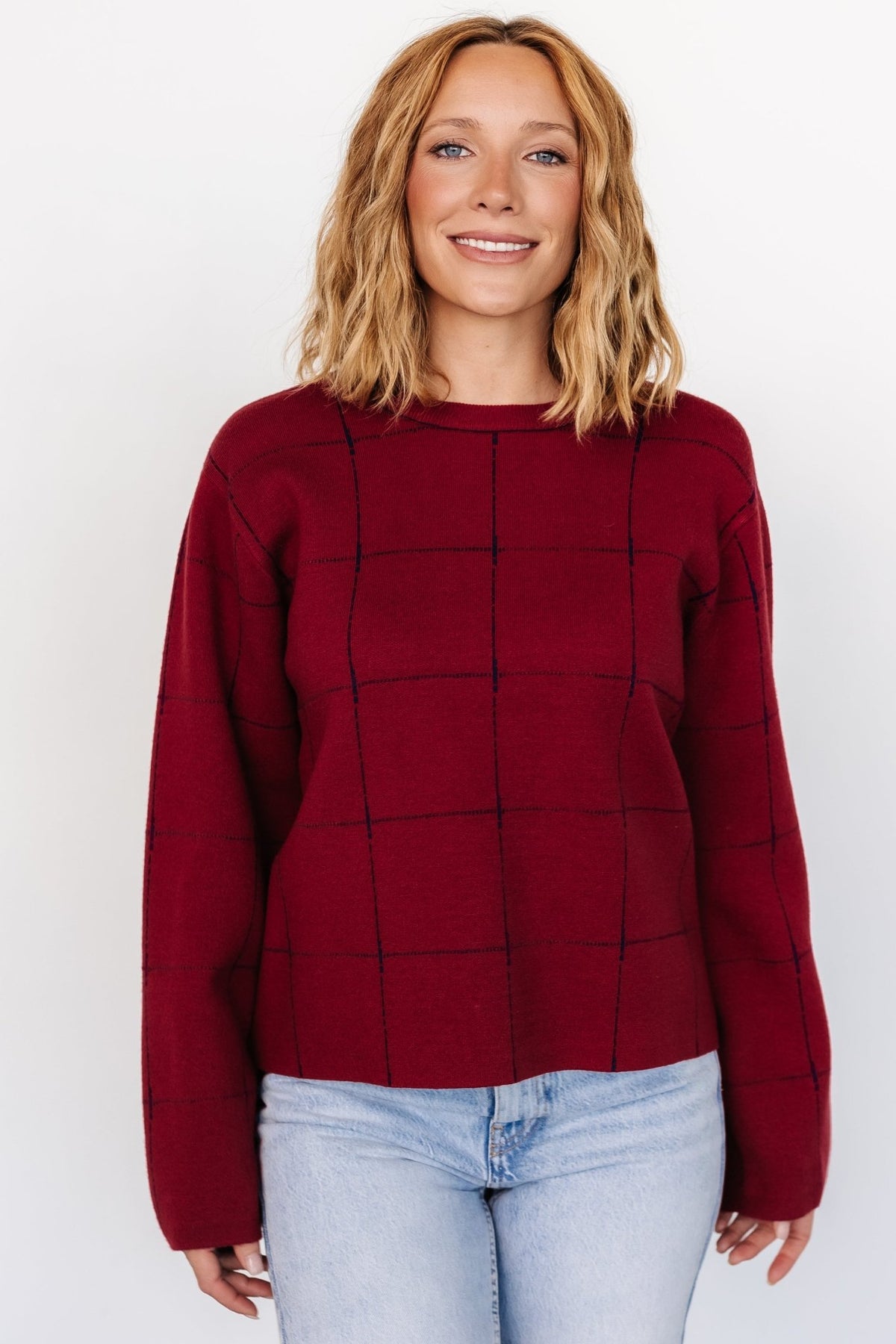Back view of the red and navy Remington Sweater on model, showing the boxy fit, straight hemline, and full-length wide uncuffed sleeves for casual styling.